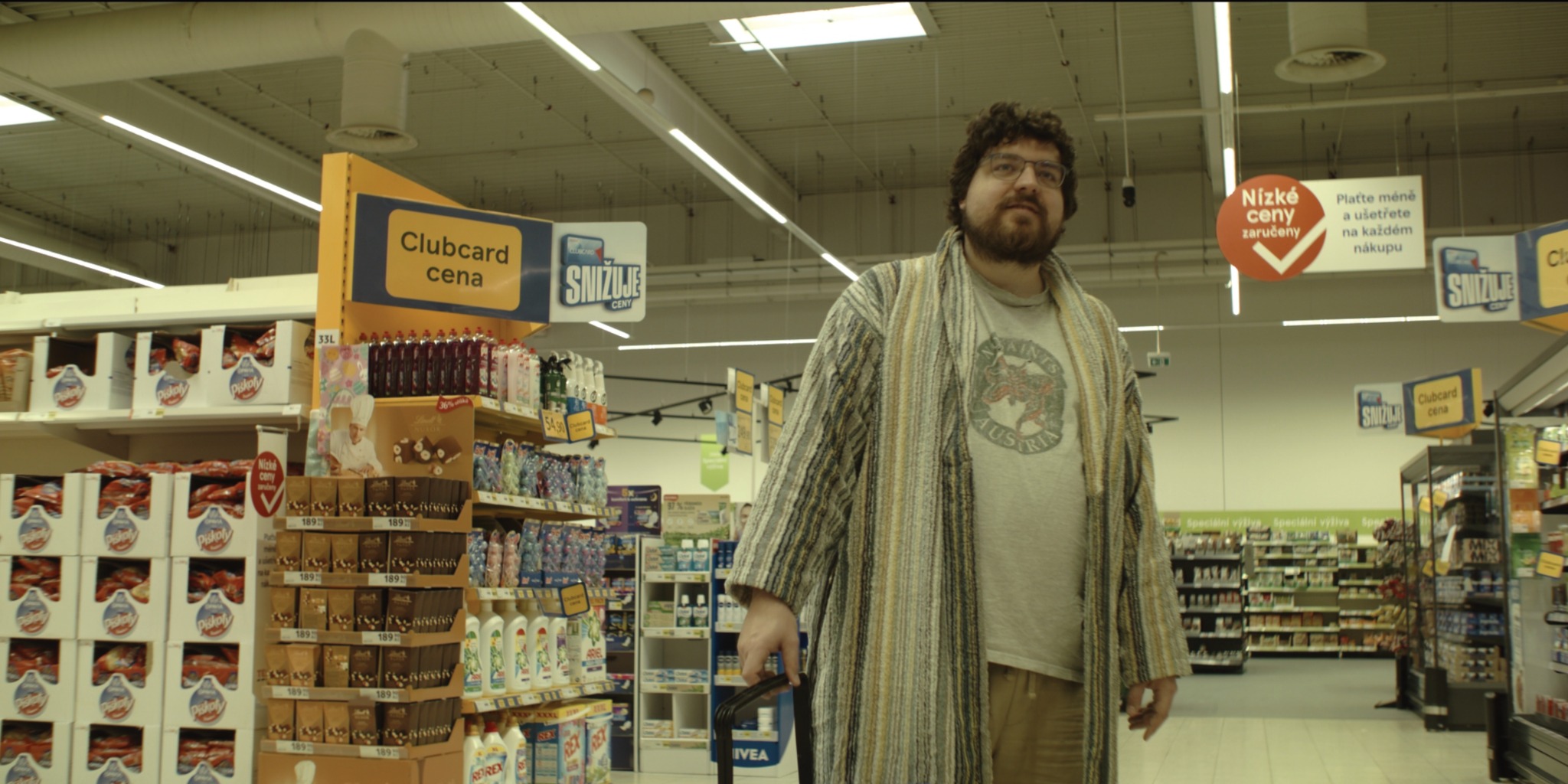 Muž v župane stojí v uličke supermarketu